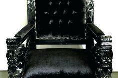 a black velvet chair with silver trimmings and birds on the armrest, in front of a white wall