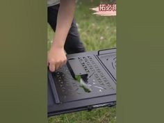 a person is using a knife to cut something on a laptop computer in the grass