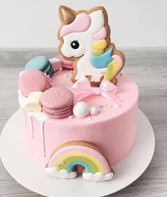 a pink cake decorated with an adorable little pony and rainbows on it's side