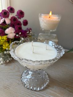 a white candle sitting on top of a glass bowl