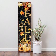 a wooden sign that says fall and has flowers on it next to a potted plant