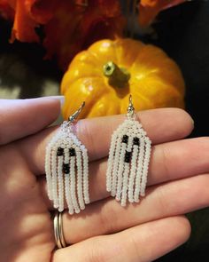 a pair of white beaded earrings with black beads and fringes hanging from them