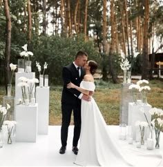 a bride and groom are standing in front of tall vases with flowers on them