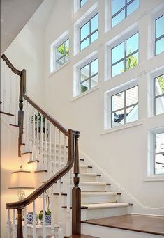 a staircase with white railing and windows above it