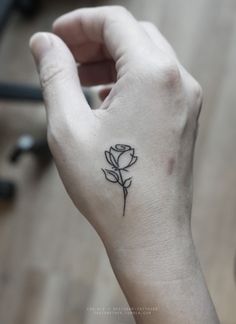 a small rose tattoo on the left hand