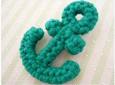 a crocheted green letter on a white surface