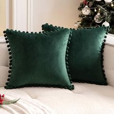 two green pillows sitting on top of a white couch