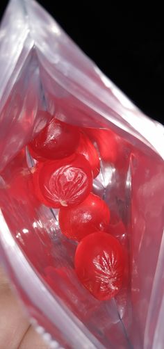 a person holding a plastic bag filled with red buttons