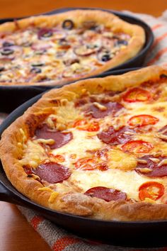 two pepperoni pizzas sitting on top of pans