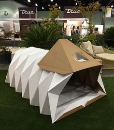 a large cardboard structure sitting on top of a lush green field