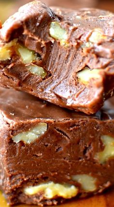 three pieces of chocolate fudge on top of each other with nuts in the background