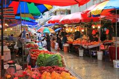 an open air market with umbrellas and various fruits and veggies for sale