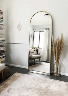 a large mirror sitting in the middle of a room next to a chair and rug