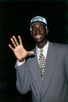 a man in a suit and tie holding his hand up