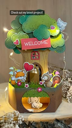 a welcome card with an image of a tree house and animals in the yard on it