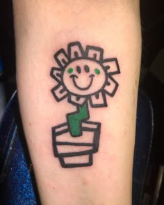 a small tattoo on the leg of a person with a sunflower in a pot