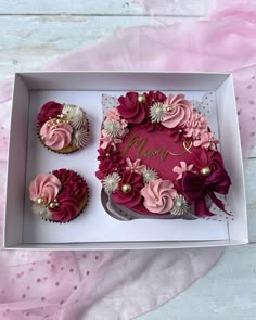 two cupcakes in a box with pink and red frosting