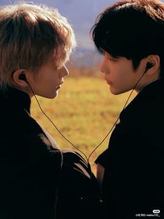 two young men standing next to each other with ear buds in their ears and looking at each other