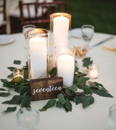 candles and greenery are arranged on the table