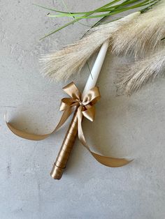 a white and gold pen with a ribbon tied around it