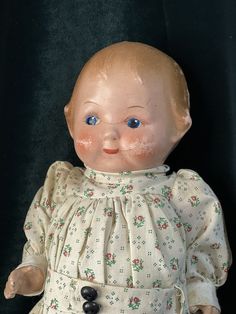 an old fashioned doll with blue eyes sitting on a black background