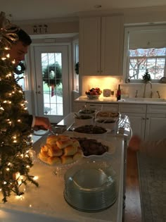 a man standing in front of a christmas tree preparing food on top of a kitchen counter