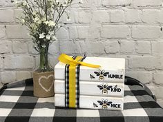 three books stacked on top of each other next to a vase with flowers