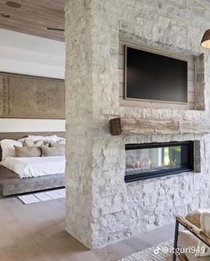 a living room with a large stone fireplace and flat screen tv mounted on the wall