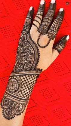 a woman's hand is decorated with hennap and beads on red fabric