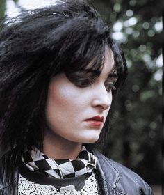 a close up of a person wearing a black and white scarf with trees in the background