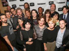 a group of people standing next to each other in front of a white sign with the words entertainment on it