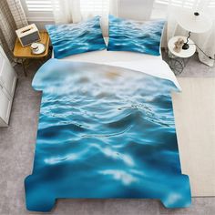 a bed with blue water printed on the sheets and pillow cases, along with a nightstand