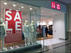 a store front with mannequins in the window and sale signs behind them