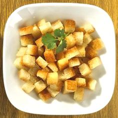 a white bowl filled with cubed bread and garnished with cilantro