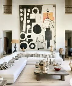 a living room filled with furniture and a large painting on the wall above it's coffee table