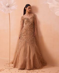 Discover a dreamy all-gold gown adorned with exquisite floral hand-embroidered motifs and shimmering zari sequins. The cape sleeves add an extra layer of elegance, making this gown a stunning choice for any special occasion. Cocktail Party Gowns Indian, Cocktail Gowns Indian Weddings, Gowns For Engagement Indian, Indo Western Dress For Wedding, Engagement Gowns Elegant, Sangeet Gown, Bridal Gowns Indian Receptions, Gown Indian Wedding, Gowns Dresses Indian Party Wear