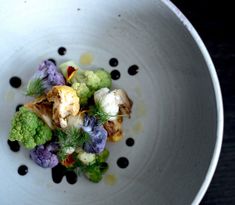 a white bowl filled with vegetables on top of a table