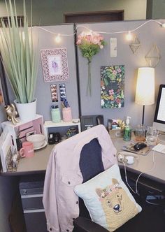 a desk with a chair, computer and flowers on the wall behind it in an office cubicle