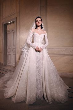 a woman in a white wedding gown with long sleeves and a veil on her head