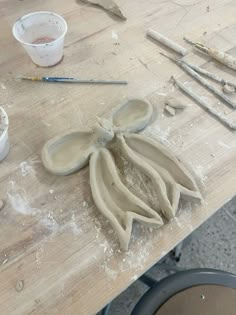 a wooden table topped with lots of white pottery and paint brushes on top of it