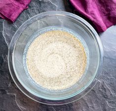 a glass bowl filled with oatmeal on top of a purple cloth next to a pink towel