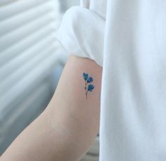 a small blue flower tattoo on the arm