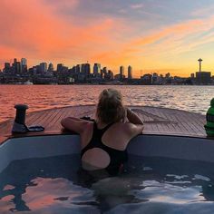 a woman sitting in the back of a boat at sunset