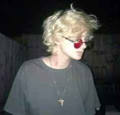 a person wearing sunglasses and a necklace with a red heart on it's face