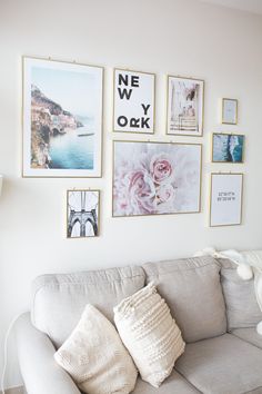 a living room with white walls and pictures on the wall above the gray couches