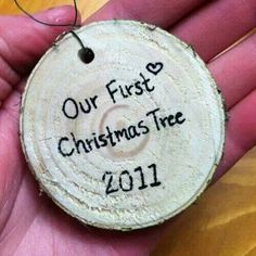 a hand holding a wooden ornament with the words our first christmas tree 2011