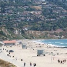 people are walking on the beach near the water