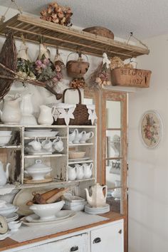 an old cabinet is filled with dishes and pans on it's shelves in the kitchen