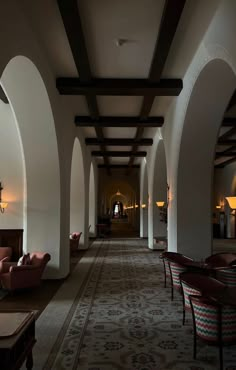 a long hallway with chairs, tables and lamps on either side of the corridor is lit by lights