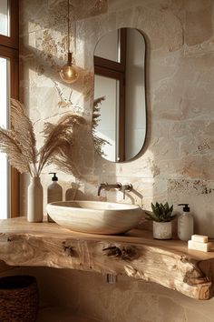 a bathroom sink sitting on top of a wooden counter next to a mirror and potted plant